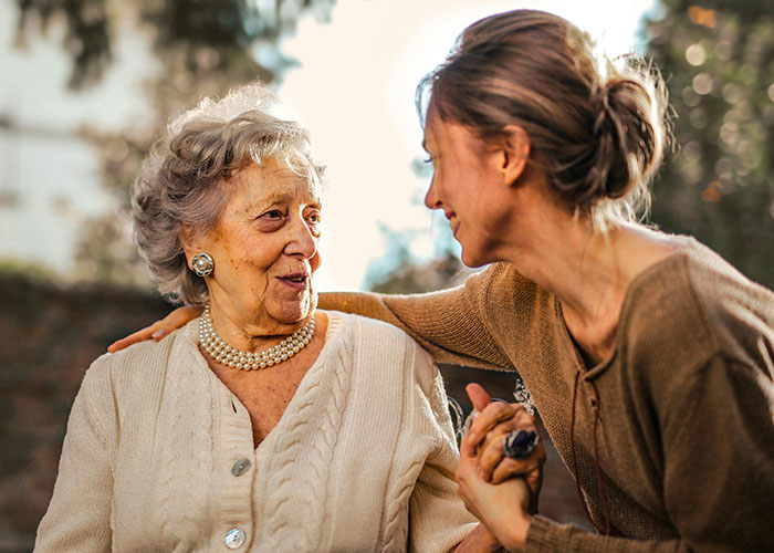 Young woman smiling at elderly woman outdoors, focus on family boundaries. Young woman smiling at elderly woman outdoors, focus on family boundaries.