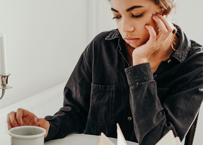 Woman in thought with coffee, reflecting on parents' reaction to her tattoo, contemplating boundaries. Woman in thought with coffee, reflecting on parents' reaction to her tattoo, contemplating boundaries.