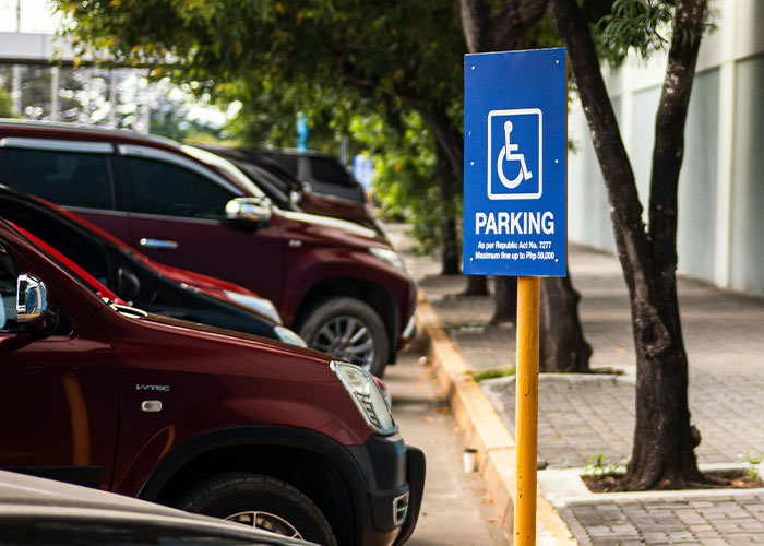 Handicapped parking sign next to a row of parked cars illustrating moments people realized their new job was a mistake.