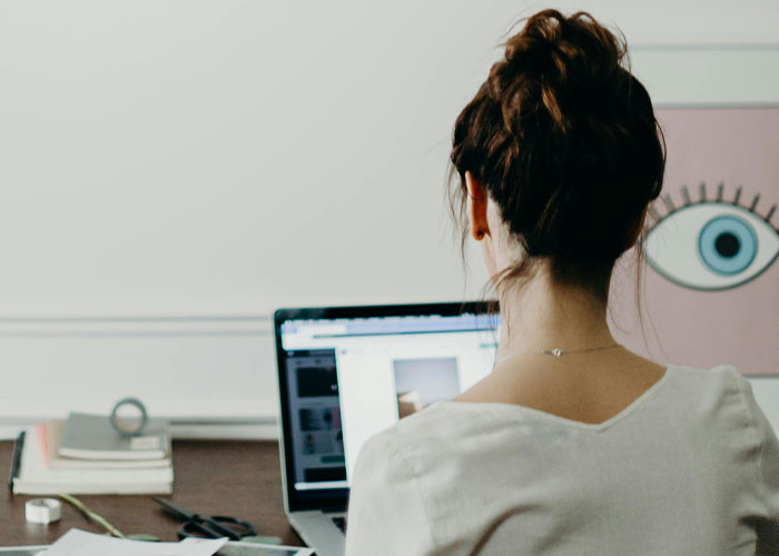 Young woman working on laptop at desk, realizing new job was a mistake and deciding to leave without looking back.