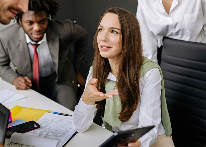 Young woman in a meeting discussing job challenges with colleagues, illustrating moments people realized their new job was a mistake.