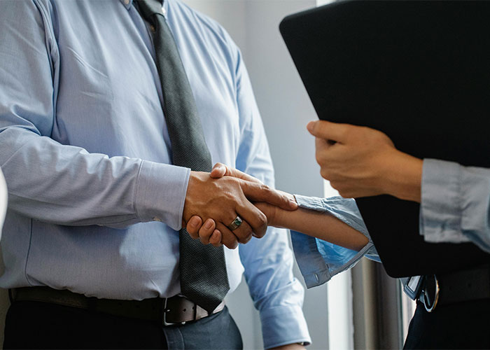 Two professionals shaking hands during a new job meeting, symbolizing the moment people realized a job mistake.