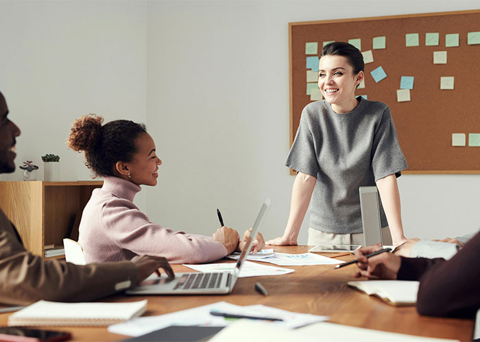 Young professionals discussing work at a table with laptops, illustrating moments people realized their new job was a mistake.
