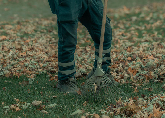 Worker in reflective pants raking leaves outside, illustrating moments people realized their new job was a mistake.