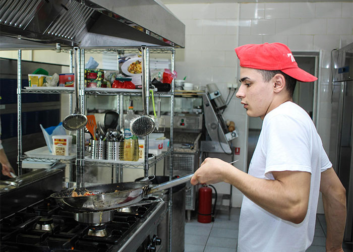 Young man cooking in a commercial kitchen, likely realizing his new job was a mistake and planning to leave without looking back.