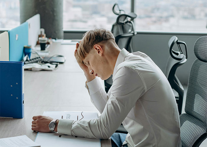 Young man in a white shirt showing stress at work, representing people realizing their new job was a mistake.
