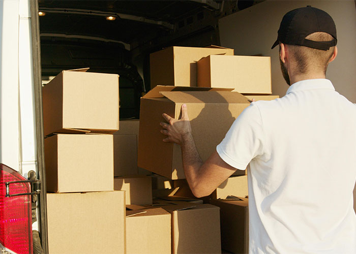 Man carrying cardboard box into van filled with packed boxes, illustrating moments people realized new job was a mistake.