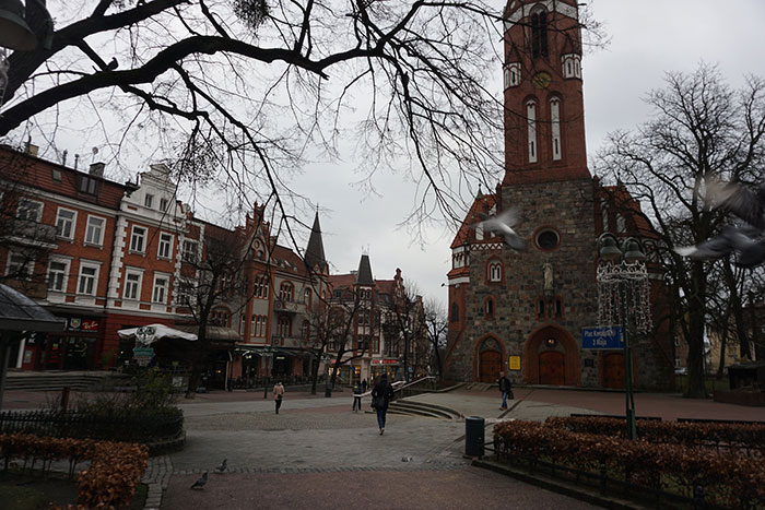 Historic European town square with brick buildings and a clock tower illustrating stereotypes about home countries.