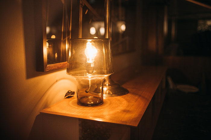 Warm light bulb inside a glass lamp on a wooden surface, illustrating cozy stereotypes about people’s home countries.