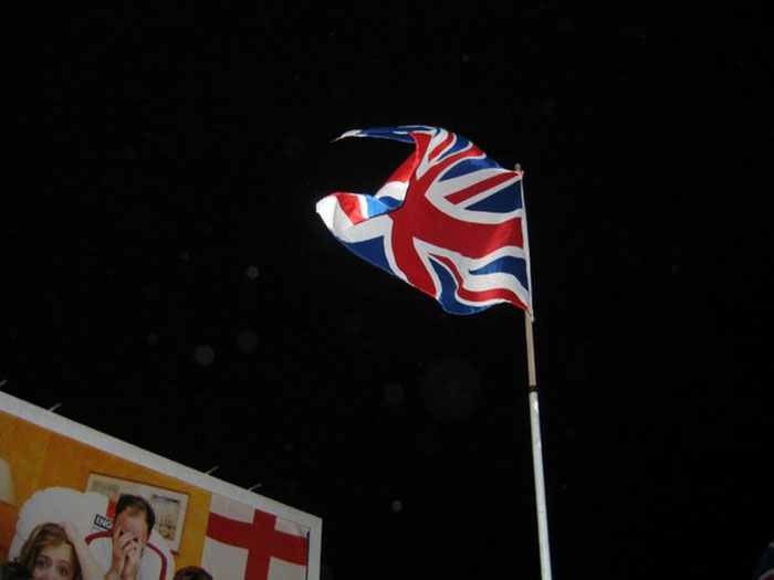 Union Jack flag flying at night representing stereotypes about people's home countries in a humorous context.