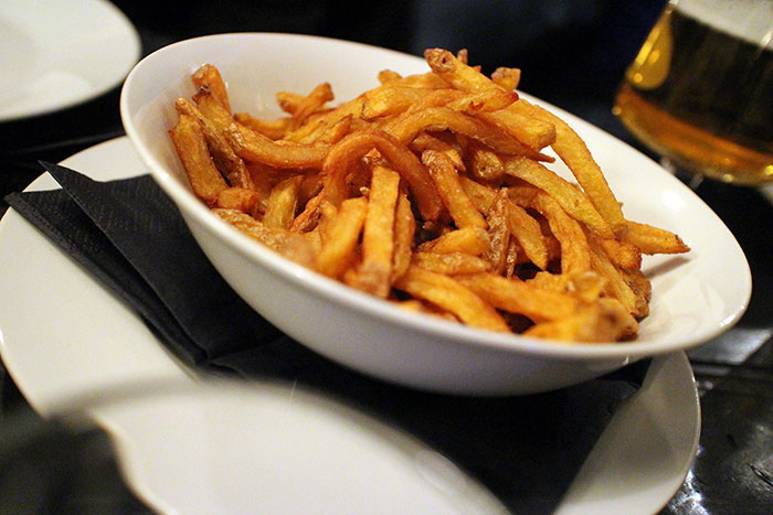 Bowl of crispy French fries on a black napkin, illustrating common food stereotypes about people's home countries.