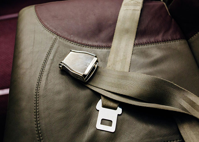 Close-up of a seatbelt buckle on a leather chair symbolizing control and manipulation in unethical parenting hacks.