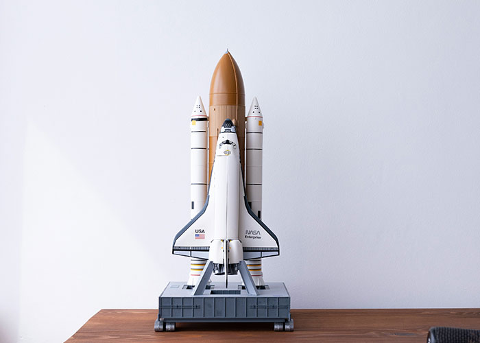 Model space shuttle on a wooden table with a plain white background illustrating unethical parenting hacks concept.