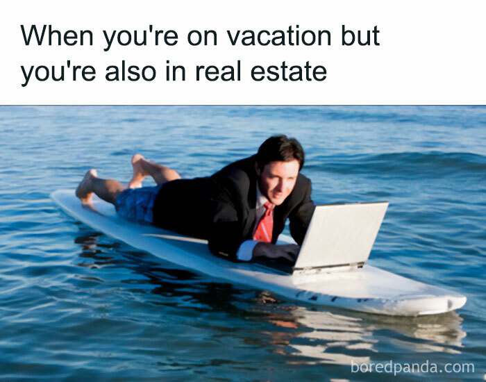 A vacation meme featuring a man in a business suit lying on a surfboard in the ocean while working on a laptop. The text above the image reads, "When you're on vacation but you're also in real estate." The image humorously depicts the challenge of balancing work and leisure.