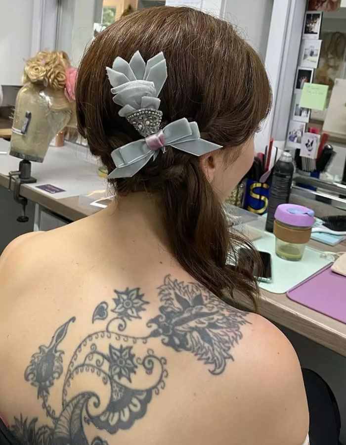 Makeup artist covers large tattoo on Claudia Jessie&rsquo;s back in a styling room.