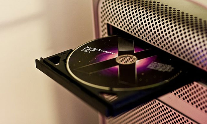 Close-up of a Mac computer with a Mac OS X Leopard installation disc in the optical drive illustrating computer understanding attempts.