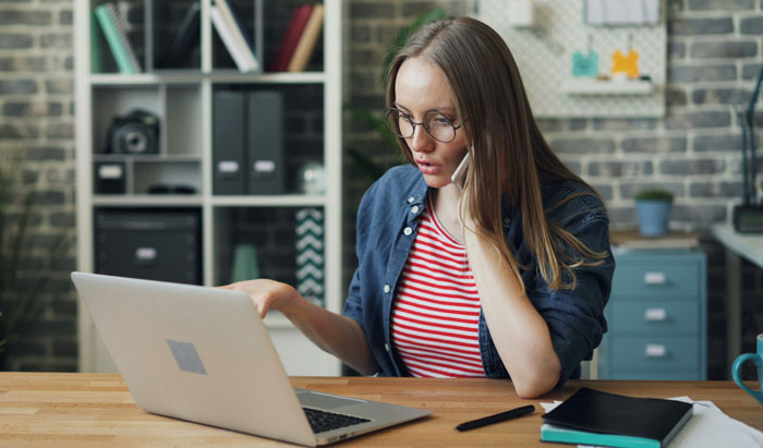 Young woman with glasses looking confused at her laptop, illustrating embarrassing attempts at understanding computers.