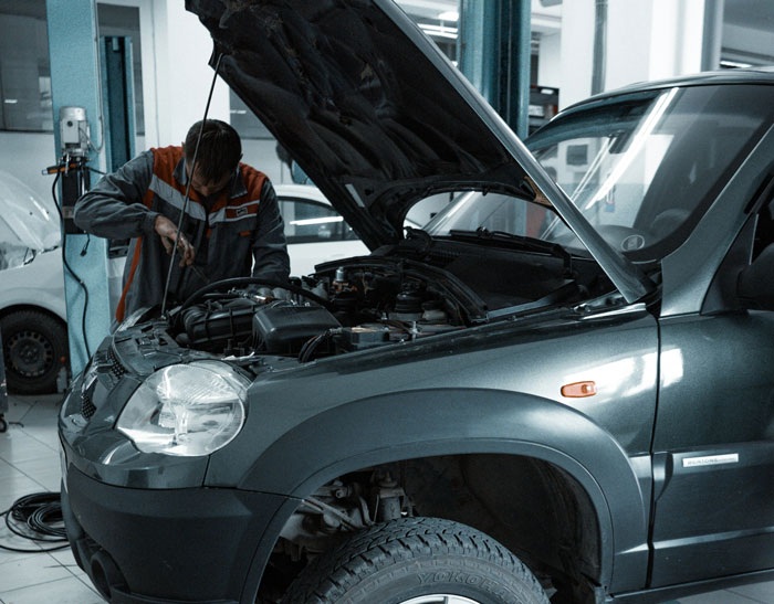 Mechanic inspecting engine under open hood of car in garage, illustrating stories of lifetime supply winnings.