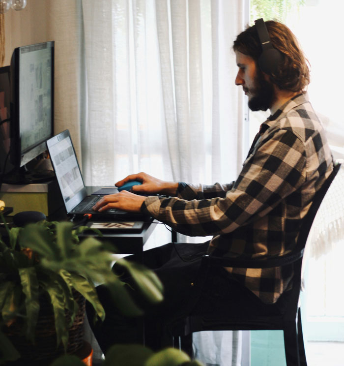 Man wearing headphones using laptop at desk, illustrating hilariously embarrassing attempts at understanding computers concept.