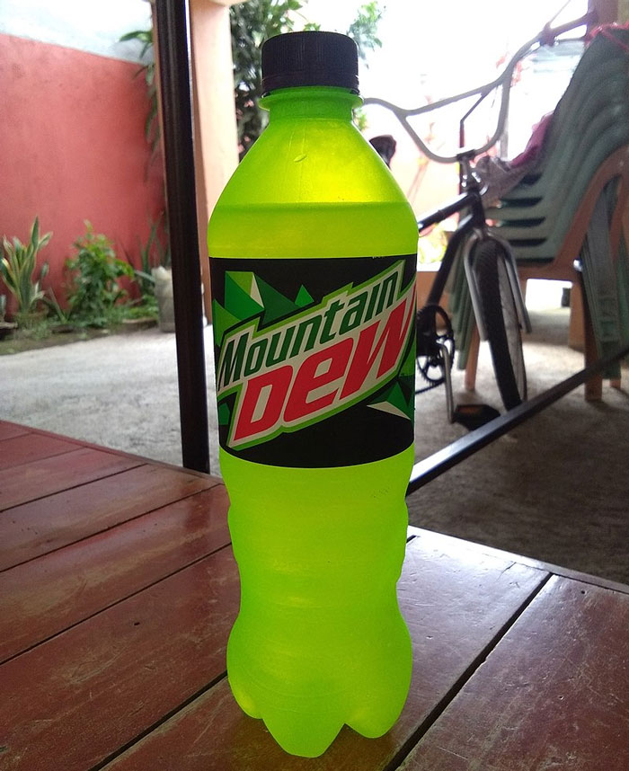Bright green Mountain Dew bottle on a wooden table, representing lifetime supply winnings in soda giveaways.