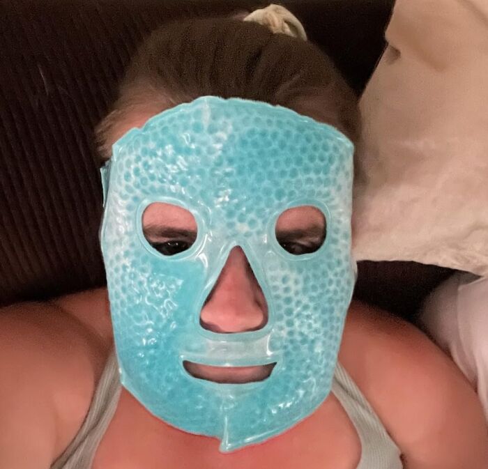 Person wearing a blue gel face mask, lying down, creating a puzzling and unexpected look.