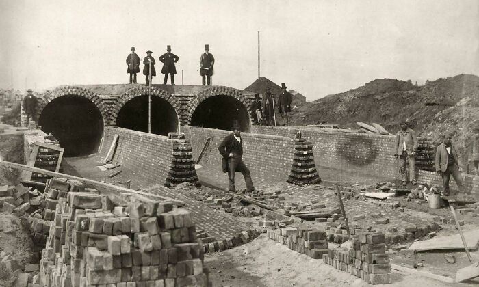 18th-century brilliant infrastructure under construction, featuring brick tunnels and workers in vintage attire on site.