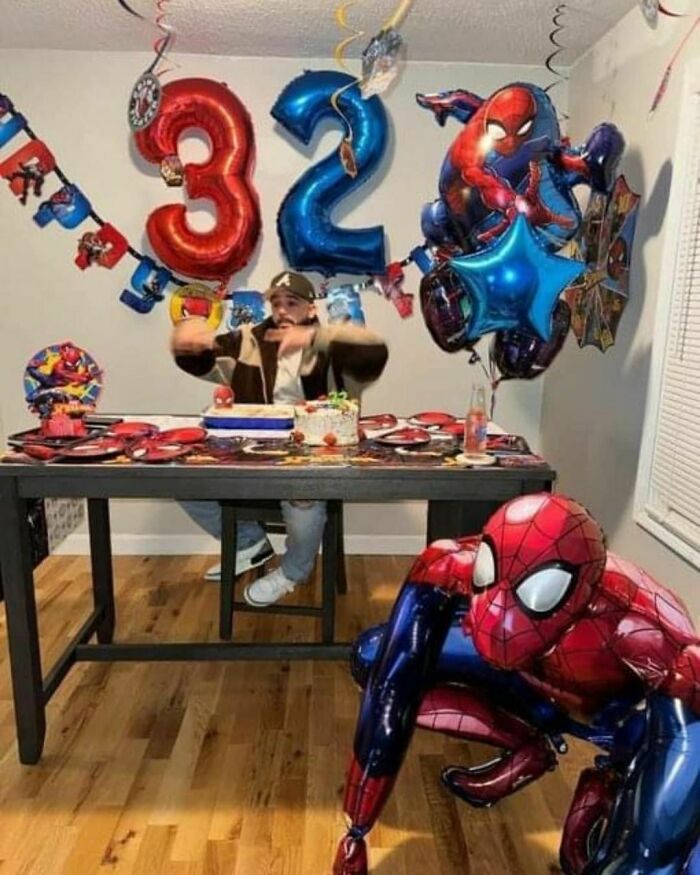 Man celebrating 32nd birthday with Spider-Man theme, colorful balloons, and festive decorations.