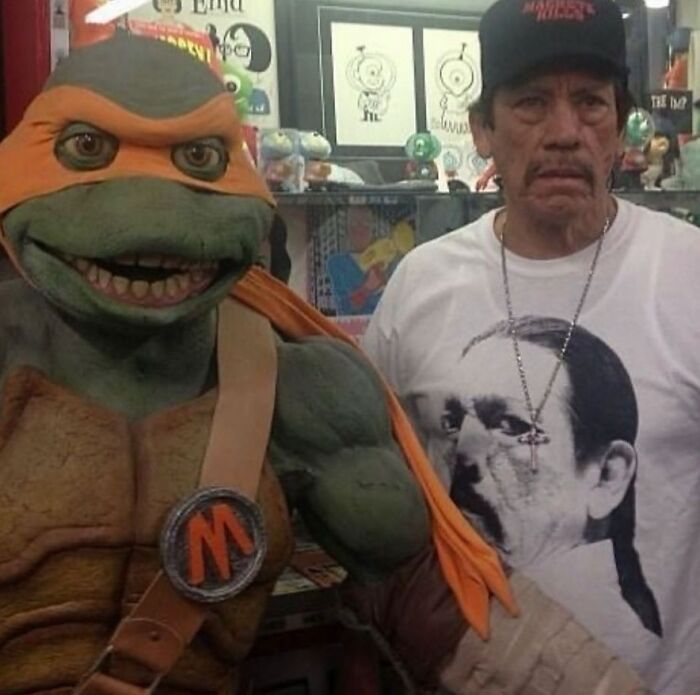 A person in a hat standing next to a costumed character, creating a humorous and striking image.