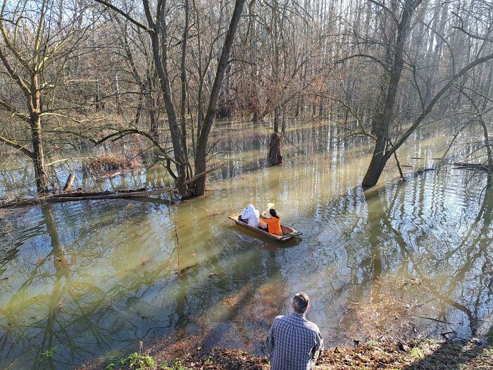 Two people paddling a small boat through a flooded forest, showcasing nature’s wild and unpredictable behavior.