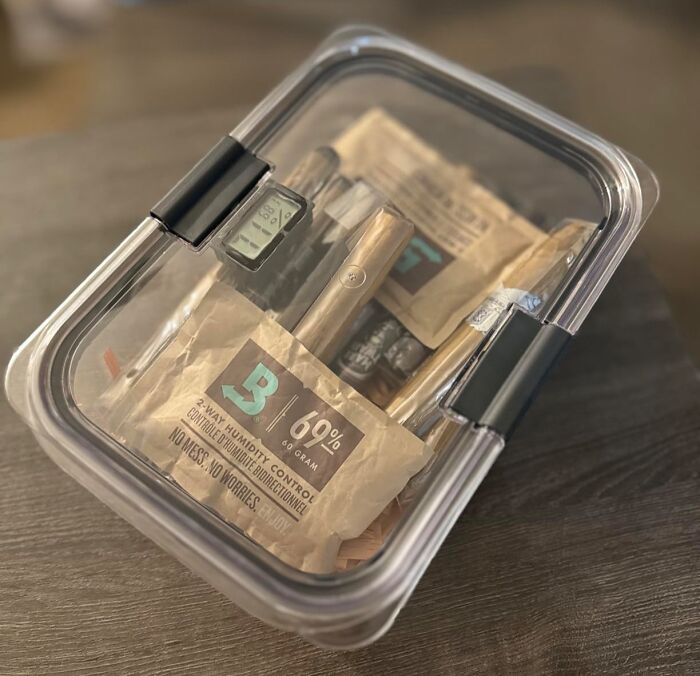 Clear plastic container with humidity control packs and a digital hygrometer, illustrating life hacks for better storage.
