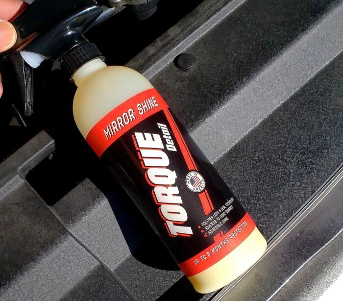 Spray bottle of Torque Detailing Mirror Shine on a black textured surface showcasing life hacks for effective cleaning.
