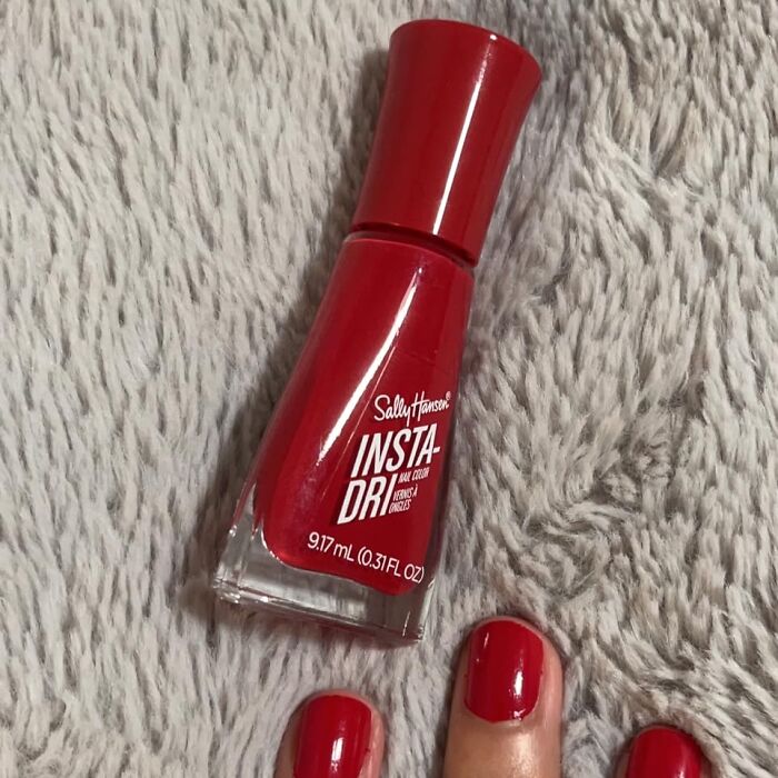 Red nail polish bottle and freshly painted nails shown as a useful life hack for quick drying nails.
