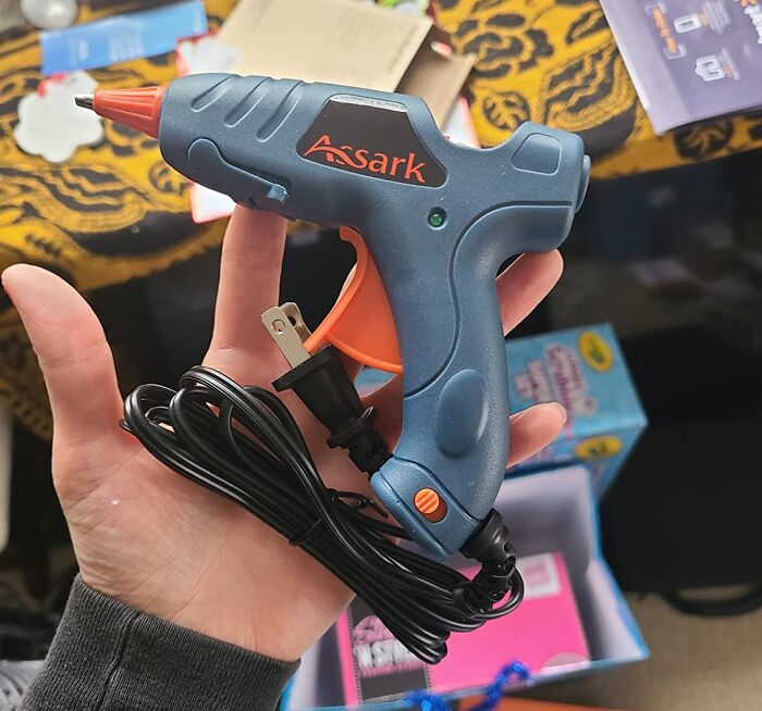 Hand holding a glue gun, demonstrating life hacks for practical and creative solutions with common tools.