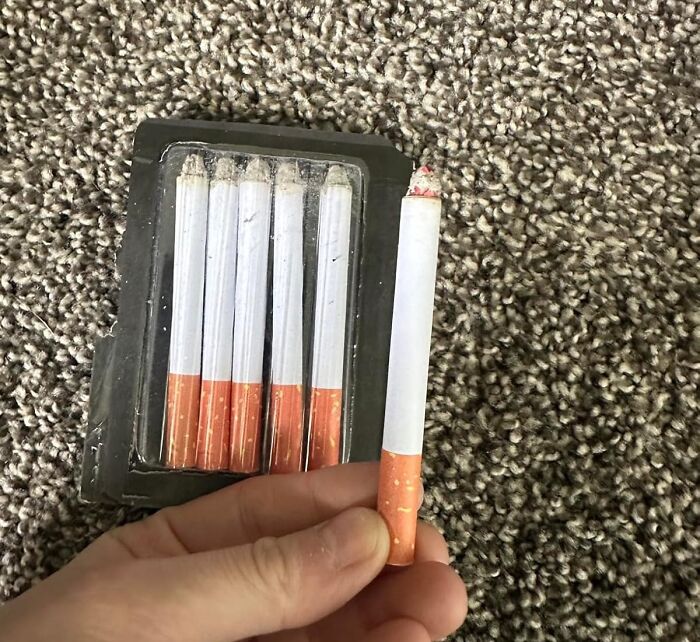 A hand holding a pencil that looks like a cigarette from a package, ideal for an April Fools prank.