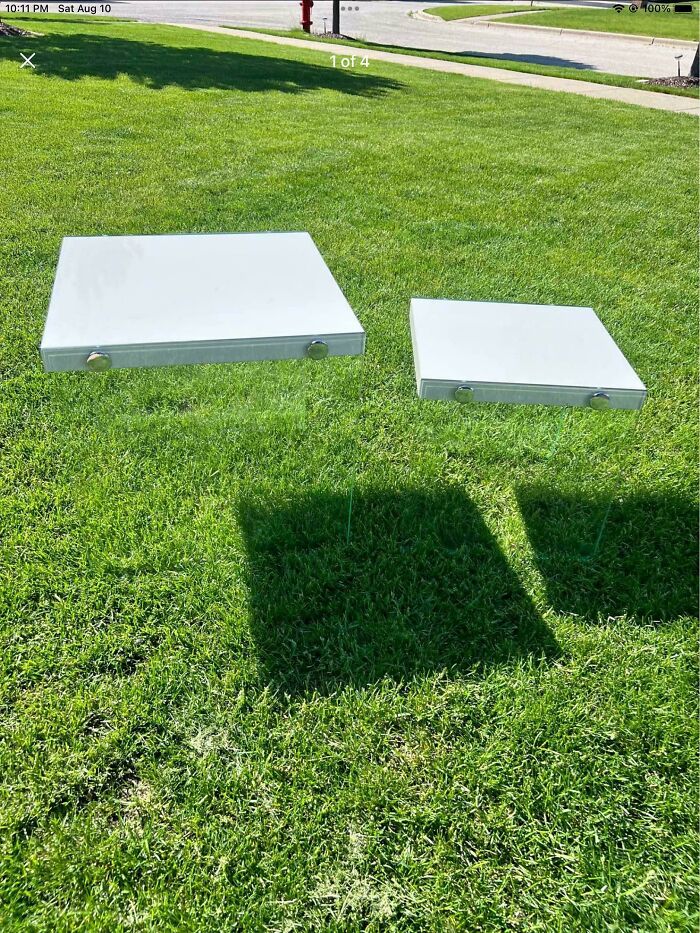 Confusing image showing trays seemingly floating above green grass in bright daylight.