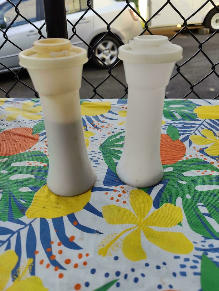Two vintage white plastic containers on a floral tablecloth, evoking nostalgia and creaking joints memories.