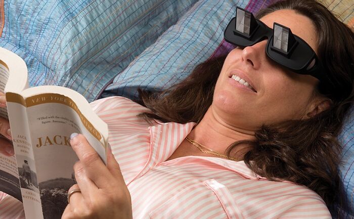Woman wearing black immersive gadget glasses while reading a book, showcasing innovative Amazon tech finds.