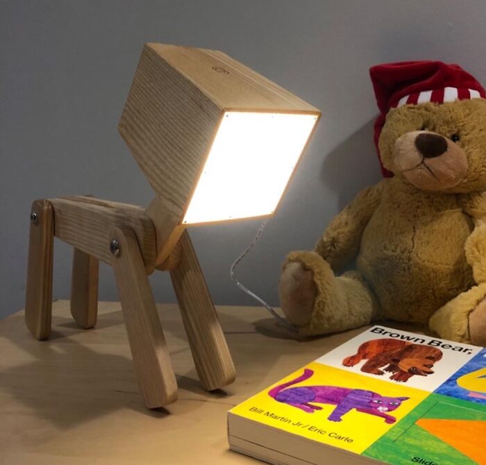 Wooden lamp resembling a dog, a teddy bear, and a "Brown Bear" book on a table, bringing inexplicable joy.