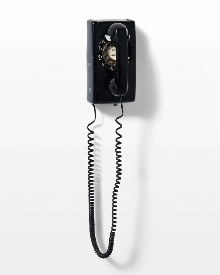 Vintage black rotary wall phone with coiled cord, a nostalgic item that may remind you of creaking joints.