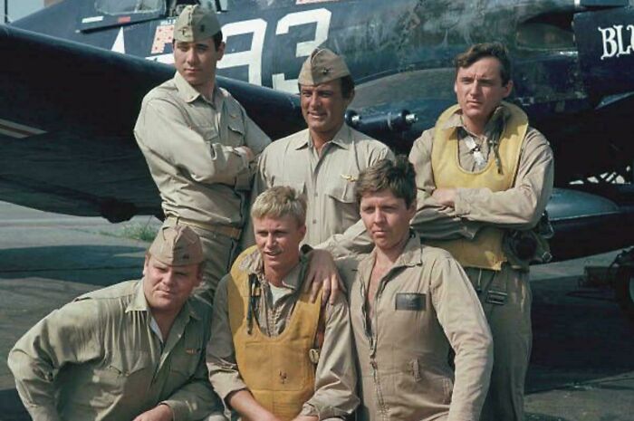 Group of World War II pilots posing in front of vintage aircraft, evoking nostalgia and creaking joints memories.
