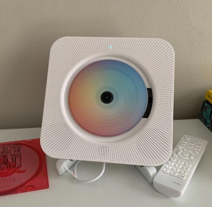 White compact CD player with colorful disc inside, remote control on desk, a popular TikTok finds gadget for home use.