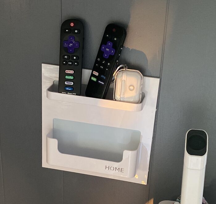 Wall-mounted organizer holding two Roku remotes and a case, a handy TikTok finds storage solution for your living space.