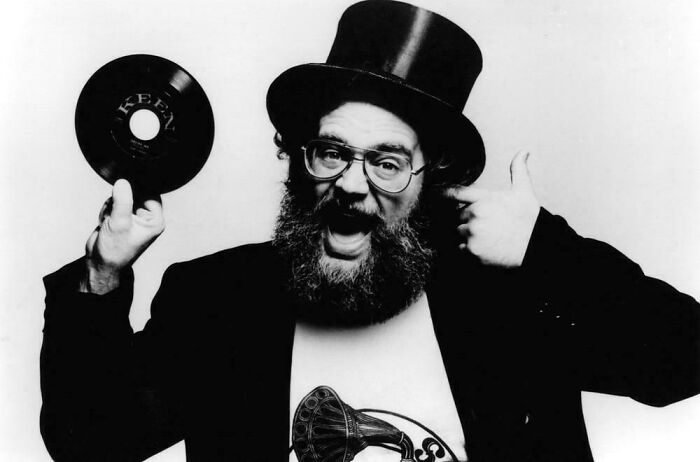 Bearded man wearing a top hat holding a vinyl record, representing nostalgic items that remind you of aging and creaking joints.