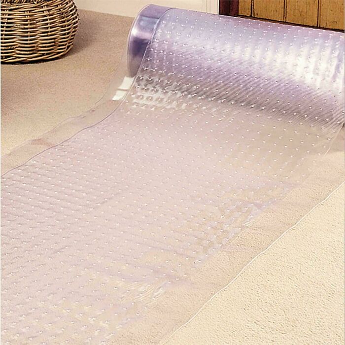 Clear plastic anti-slip bath mat roll with suction cups against carpet and wicker basket, nostalgic item for creaking joints.