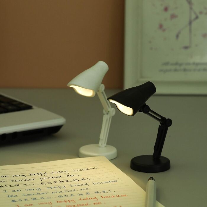 Small white and black desk lamps illuminating a notebook and pen, perfect for dorm finds to survive freshman year.