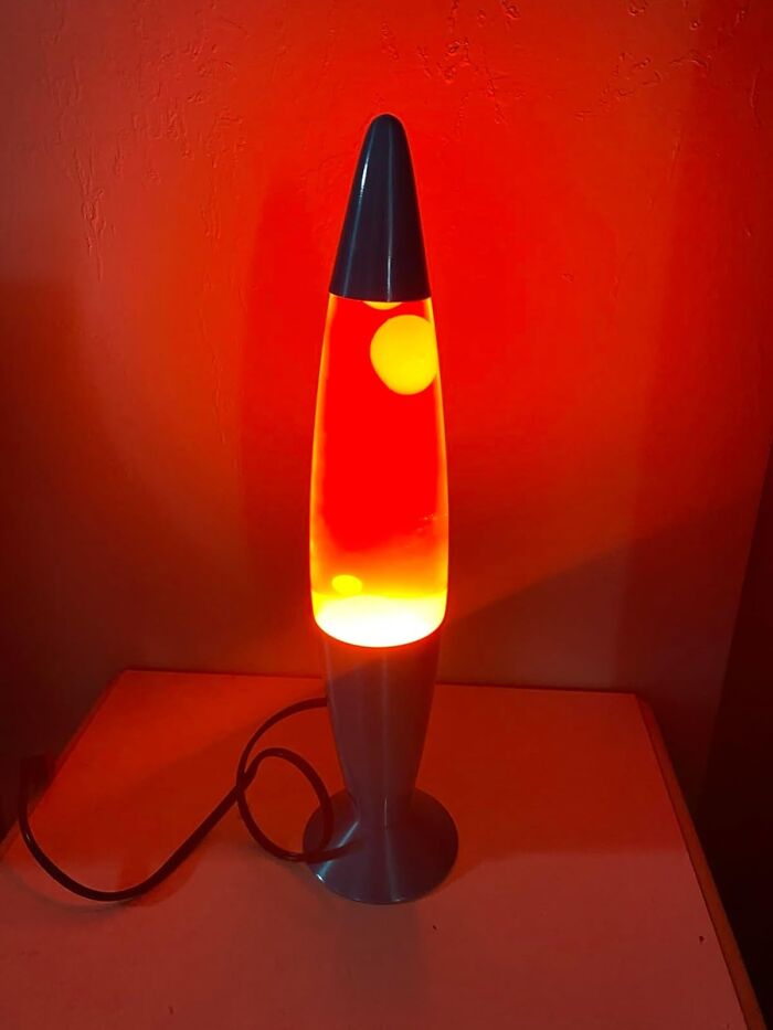 Lava lamp glowing orange on a table, a genius dorm find to help survive freshman year dorm life.