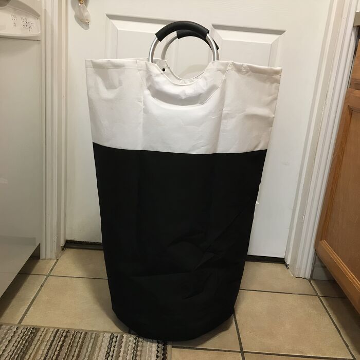Large black and white laundry hamper with round handles ideal for easy dorm room organization and storage.
