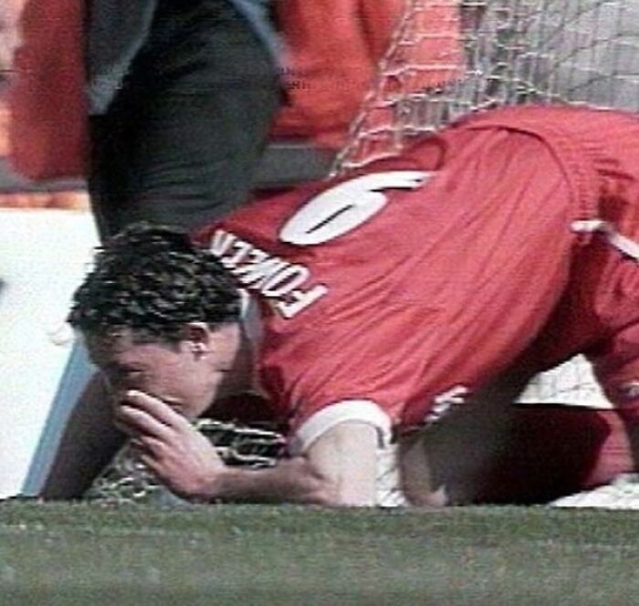 Soccer player in ‘90s kneels on field, wearing red jersey with number six.