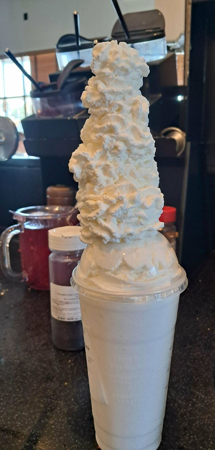 Milkshake with an extra tall stack of whipped cream, showing a fun customer request complied by food service workers.