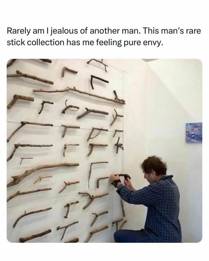 Man organizing a unique stick collection on a wall, showcasing creativity and humor for meme enthusiasts.